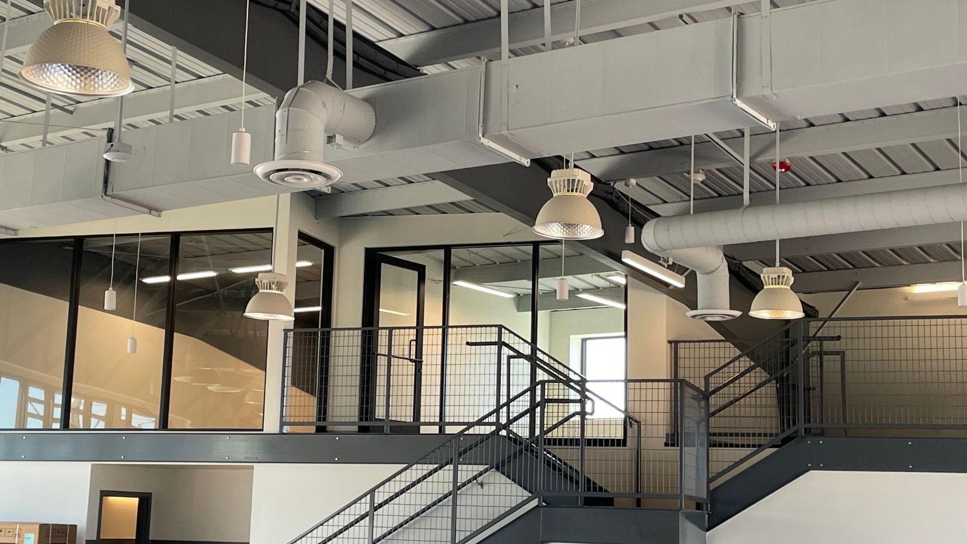 Open communal workspace with suspended PoE high bay fixtures and wireless wall switches