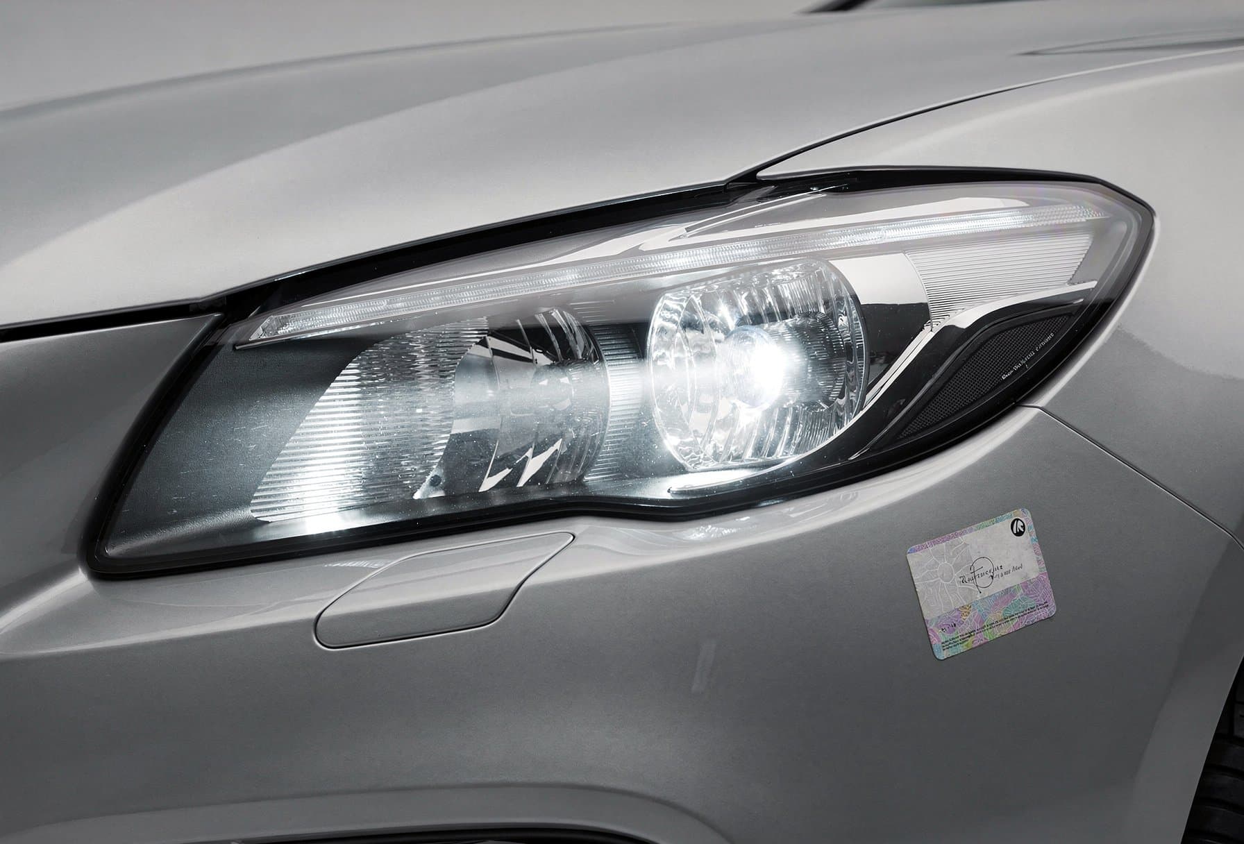 MOT tester inspecting a car headlamp with an LED replacement sticker visible