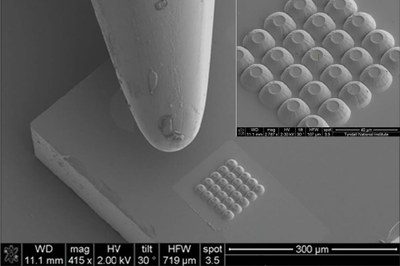 A cluster of 25 MicroLEDs beside the tip of a needle. The parabolic reflector shape can be seen in the inset close-up