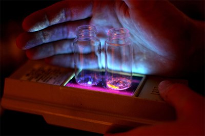 Organic phosphors developed at the University of Michigan could one day lead to cheaper organic light-emitting diodes. Here, they glow in blue and orange when triggered by ultraviolet light. (Credit: Marcin Szczepanski, U-M College of Engineering)