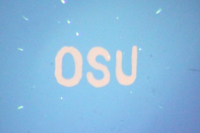 The orange color in the letters “OSU” is produced from “quantum dots” viewed under a microscope, as they absorb blue light and emit the light as orange – an illustration of some of the potential of new technology being developed at Oregon State University. (Image courtesy of Oregon State University)